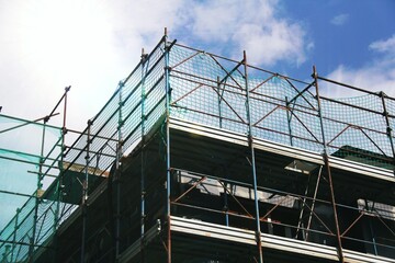 Shot of industrial restoration of a house in the top floor , with a blue sky as background .