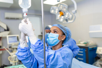 African american female Doctor in the operating room putting drugs through an IV - surgery concepts