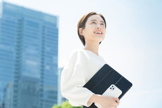 オフィス街に立つ笑顔の女性