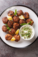 Greek Traditional Meatballs Keftedakia served with Tzatziki sauce closeup in the plate on the table. Vertical top view from above