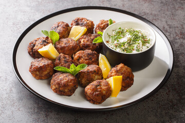 Keftedakia is a Greek traditional dish that is created with minced beef and bread crumbs rolled into balls and fried closeup on a white plate on a table. Horizontal
