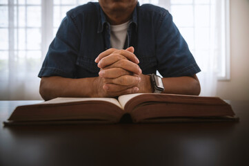 Hands of a man pray on bible, hope, faith, christianity, religion concept.