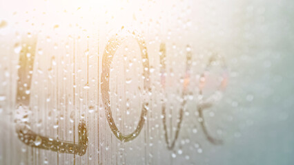 word Love on window glass covered with fog. Romantic inscription on misty window glass written by man missing lover, closeup