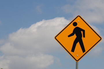 Pedestrian walking sign against blue sky with clouds