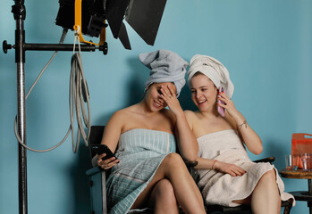2 young models are waiting in a photo studio for their job to continue. They are lauging and...