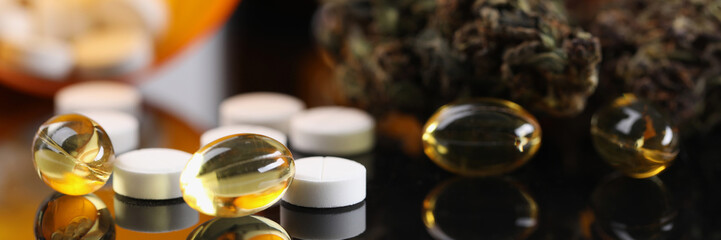 Prescription marijuana buds and yellow and white pill capsule