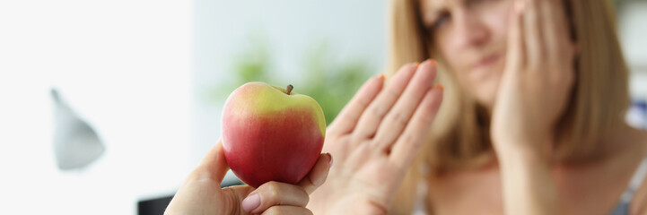 Person give apple to friend and woman refuse to eat because of tooth pain