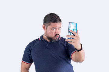 A man in his 30s takes a funny selfie with his phone. Making a hilarious duck face. Isolated on a...