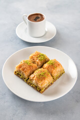 Pistachio baklava on a white plate with Turkish coffee.Traditional Turkish baklava and t coffee on a white background