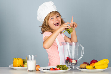 Child chef isolated on blue. Funny little kid chef cook wearing uniform cook cap and apron cooked food in the kitchen.