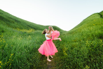 Young mother hugging daughter. Family holiday in the park. Portrait mom with child together on nature. Mum with a little girl walking outdoors. Happy Mothers Day. Family look. Close up.