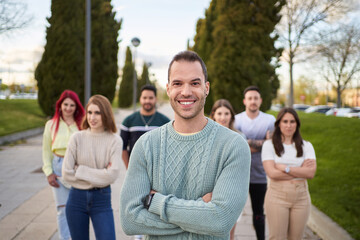 Man smiling looking at the camera while standing in front of a group of people.. Team and leadership concept.