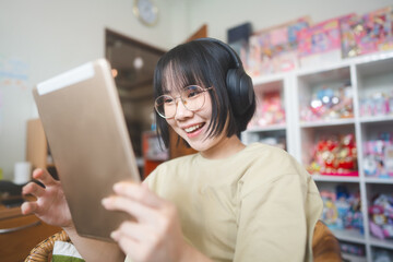 Young adult asian woman wear headphone listen music and relax using digital tablet for surfing the net