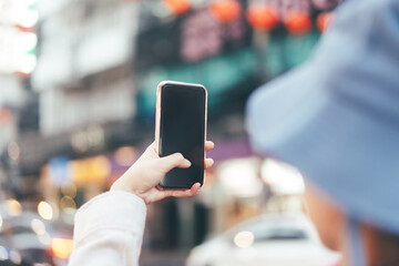 Woman hand holding a smart phone at outdoor for online digital application with light bokeh