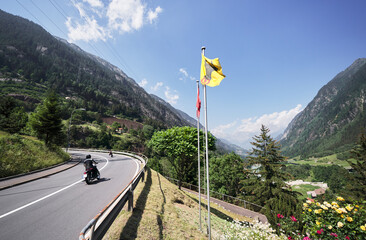 The flag of canton Uri. The road in the Swiss Alps Mountains. Travel by Switzerland.