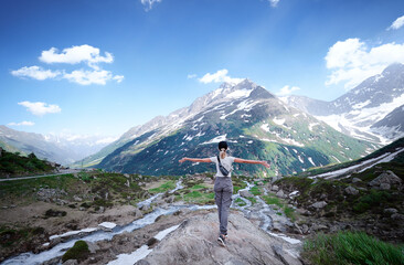 Fototapeta na wymiar Travel by Swiss Alps. Young woman enjoying the mountains view with hands up.