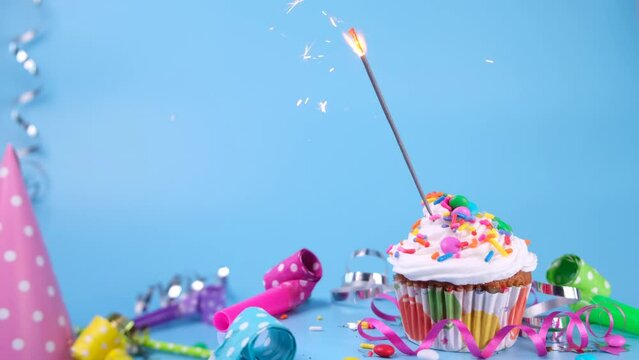 Birthday cake or cupcake with a burning sparkler on a blue background. Party, birthday or anniversary celebration concept with place for text ,copy space 