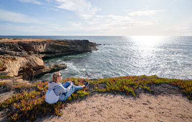 Fototapeta na wymiar Tourism concept. Young traveling woman with rucksack enjoying ocean view.