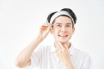白背景で眉毛を切る男性