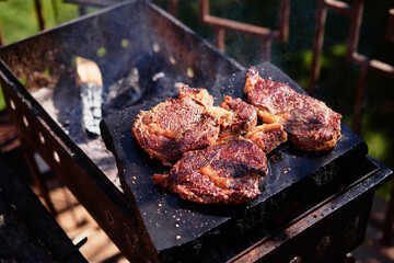 Raw beef burger steak on grill. Cutlet meat placed on grill stone with fire.