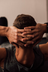 Fototapeta na wymiar Strong male hands behind the head of an athlete who performs a sports exercise