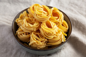 Homemade Organic Dry Tagliatelle Pasta in a Bowl, side view.