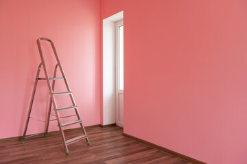 Foldable chrome stepladder against blank wall indoors