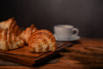 Close up tasty buttery croissants on black wooden table with hot coffee for breakfast