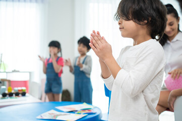 Group of Mixed race cute child standing clapping hands in classroom. 