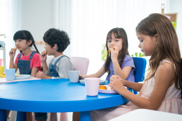 Mixed race Group of young girl eating foods during break in classroom.