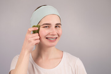 Close-up portrait of a smiling woman with braces doing home care with a gouache massager.