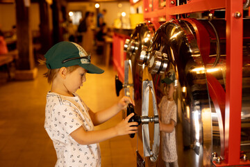 Preschool child, standing next to a barrel brewer for beer in a bar