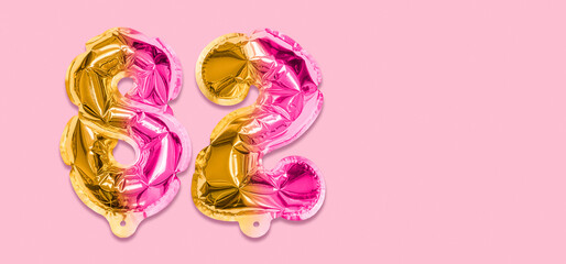 Rainbow foil balloon number, digit eighty two on a pink background. Birthday greeting card with inscription 82. Top view. Numerical digit. Celebration event, template. Banner