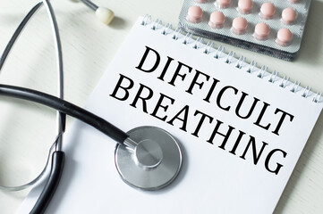 Medical concept. DIFFICULTY BREATHING text on a notebook side by side on a stethoscope table and tablets