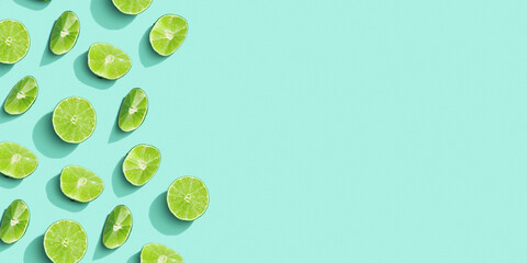 Citrus lime fruit as creative background, slices of green lime with hard shadows at sunlight on pastel mint background with copy space. Fruits food concept. Top view, monochrome colored
