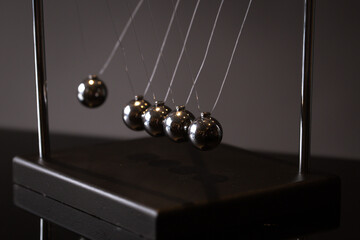 Closeup metal Newton cradle placed on gray background as representation of momentum concept