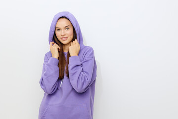 a relaxed woman stands on a gray background in a purple tracksuit wearing a hood on her head holding her neck with both hands