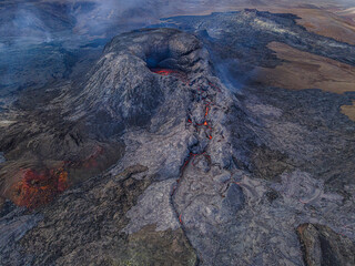 Top view of active volcano on Reykjanes peninsula at day. Volcanic crater in Iceland. Dark magma rock around the crater with little smoke. small lava flows in the crater before the eruption. © Marco