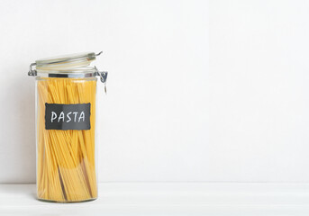 Organization of storage in the kitchen. Pasta in glass container on a kitchen table. Zero waste storage.