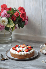Side view on sweet creamy cake with berries and tea on grey background