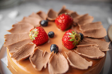 Closeup on caramel glazed cake with berries and cup of tea