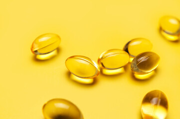 Fototapeta na wymiar Capsules pill with vitamin D on yellow background close-up. Fish oil, Omega, Omega-3, dietary supplement, sunshine vitamin. Healthy lifestyle, medicine, cosmetology, diet. Pharmaceutical concept