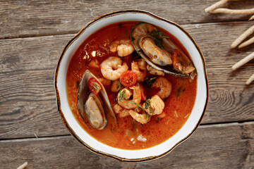 Top view on bowl of tom yam soup on wooden background