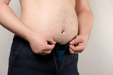 A man tries to fasten his small pants. The concept of male obesity, excess weight