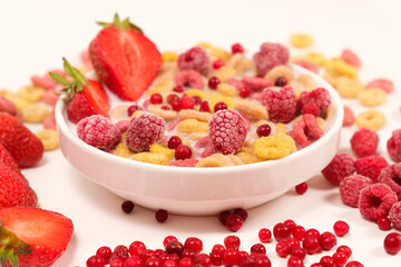 Corn rings with milk in a plate with berries and fruits, side view on a white background. The concept of quick breakfast cereals