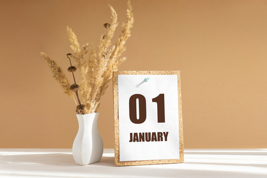 january 1. 1th day of month, calendar date.White vase with dried flowers on desktop in rays of sunlight on white-beige background. Concept of day of year, time planner, winter month