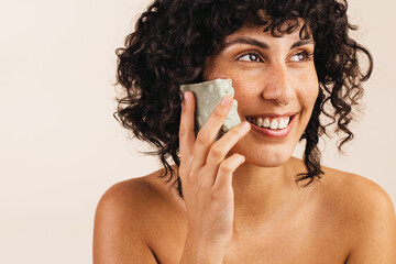 Beautiful young woman holding a bar of natural soap - obrazy, fototapety, plakaty