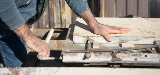 Electric tile cutter. Tiler cutting tile on wet saw machine
