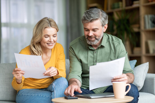 Middle aged spouses checking financial documentation while planning family budget at home