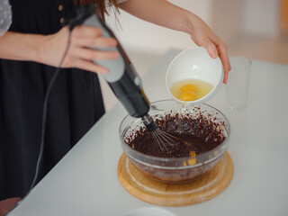 woman mix cocoa powder, sugar and flour to make dough with melted chocolate and walnuts for delicious homemade brownie cake. cake homemade by housewife concept.